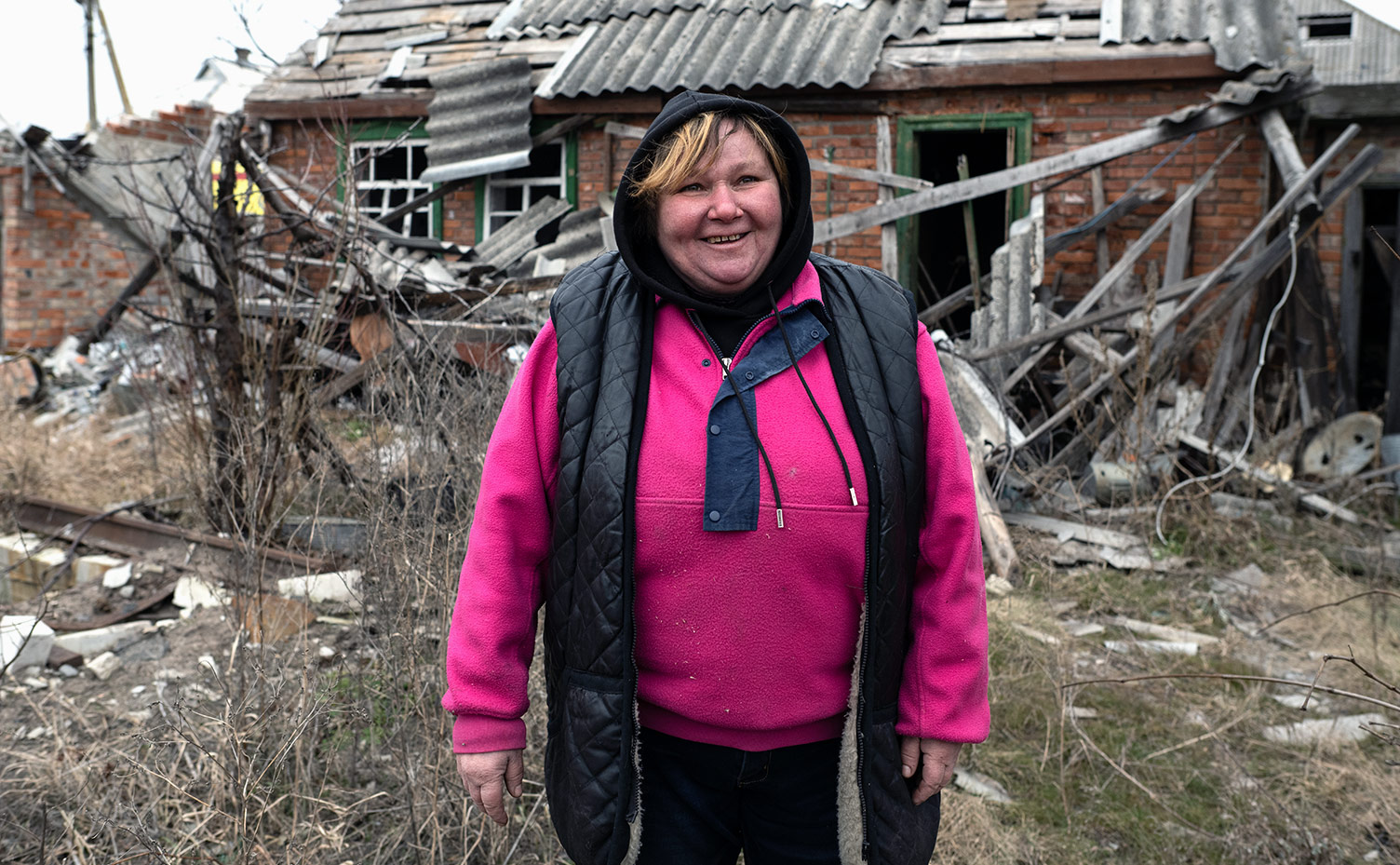 Olga stands in front of her property ruined by war.