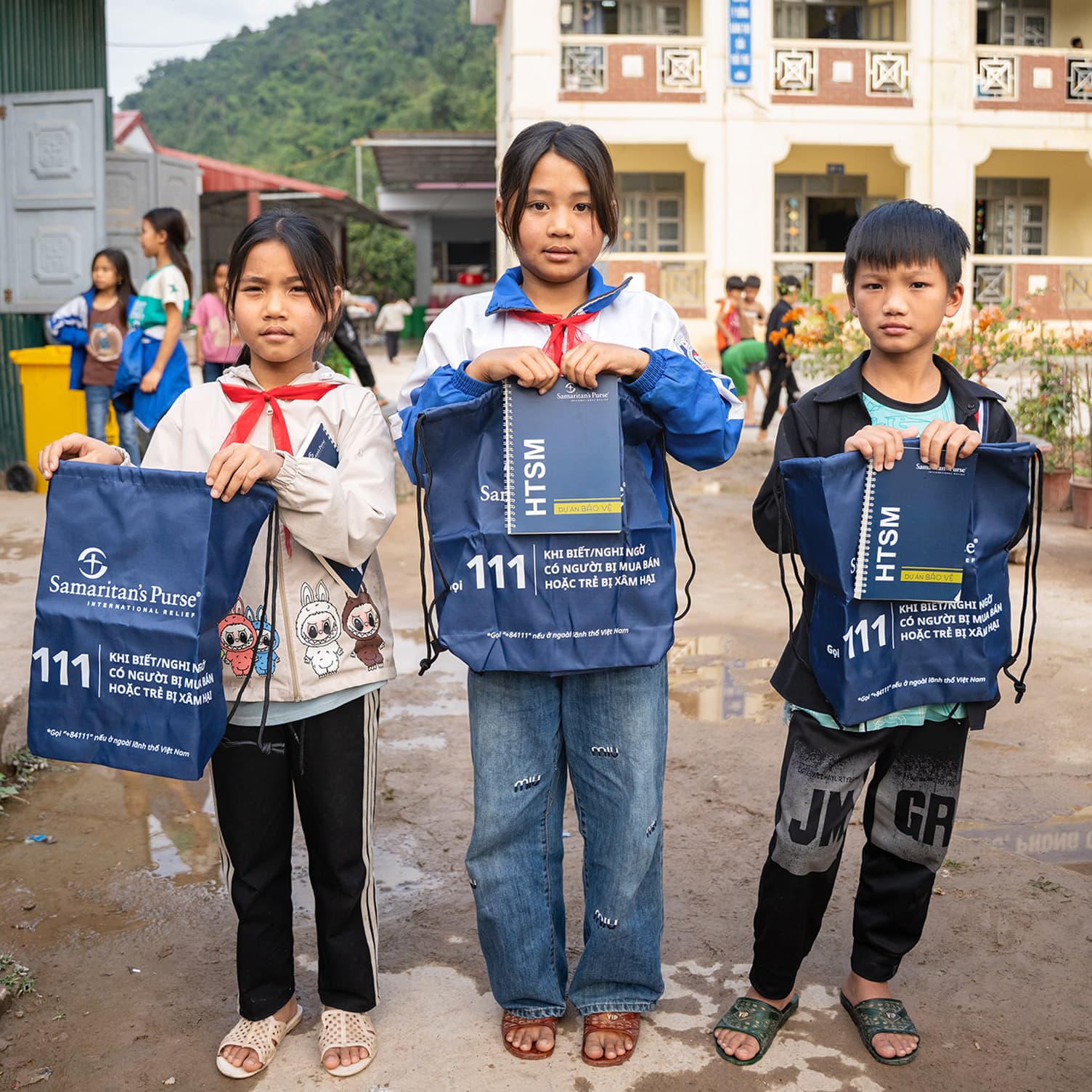 Three children with Samaritan's Purse backpacks and books.