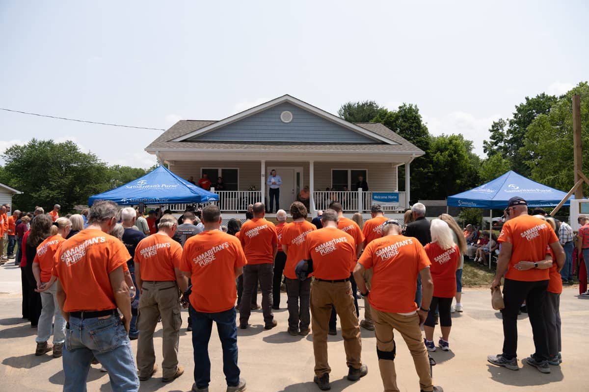 Volunteers standing in front of a home being dedicated to family.
