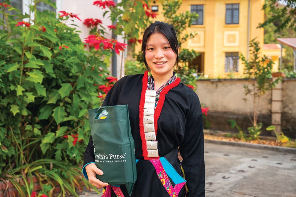 A woman holding a bag while smiling.