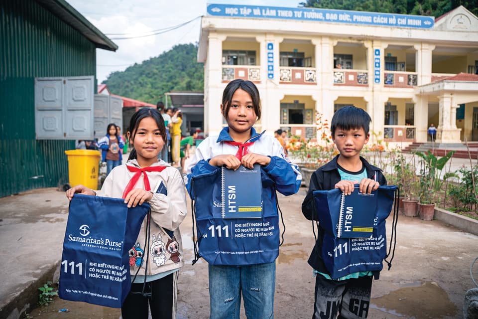 Two girls and one boy holding bags.