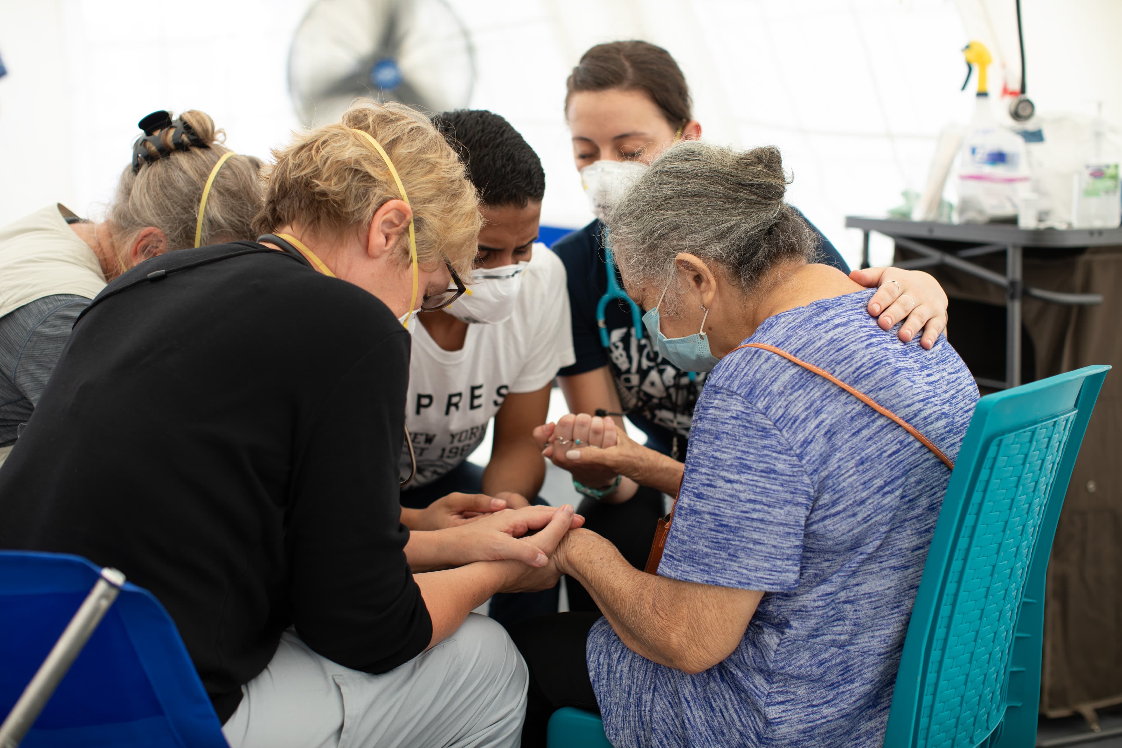 A group of people praying for elderly lady.