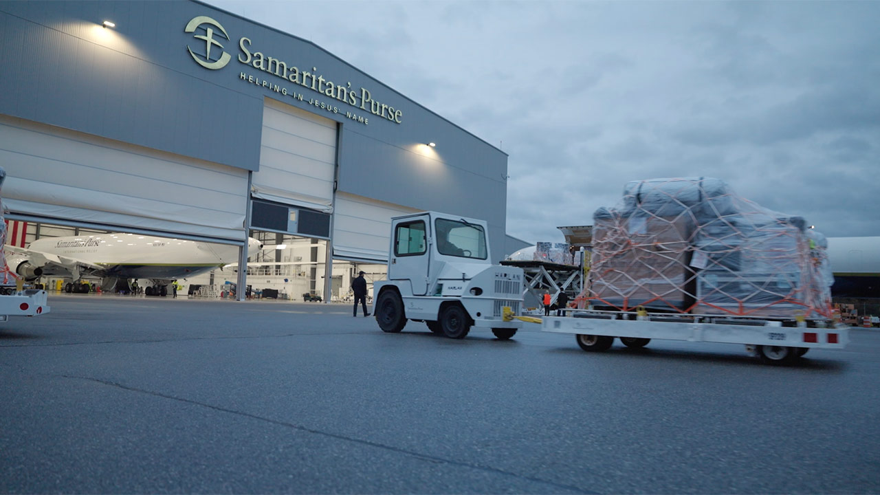 A heavy machine pulling some cargo into a airplane hanger.