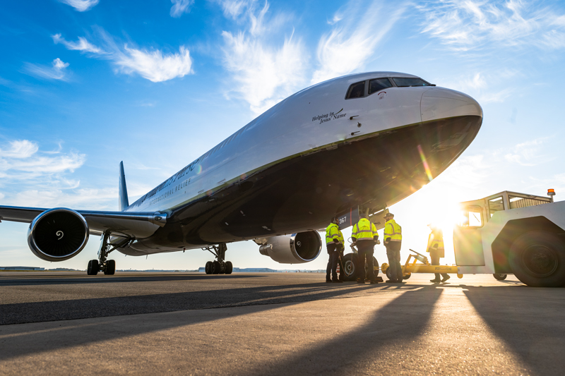 A group of flight professional standing in front of a airplane.