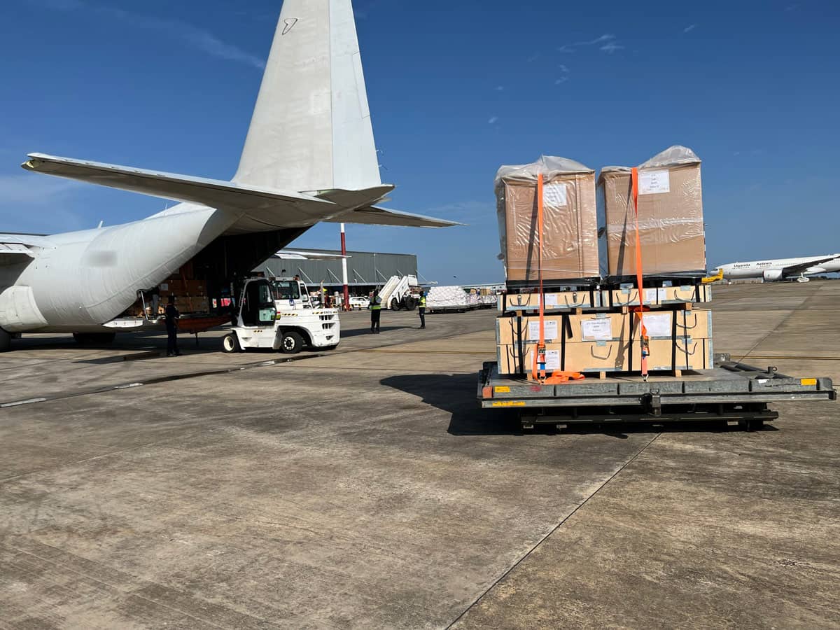 A large forklift loading a crate of supplies into an airplane.