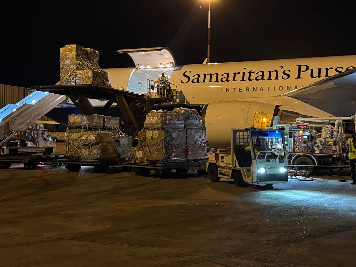 A heavy lift loading supplies into an airplane.