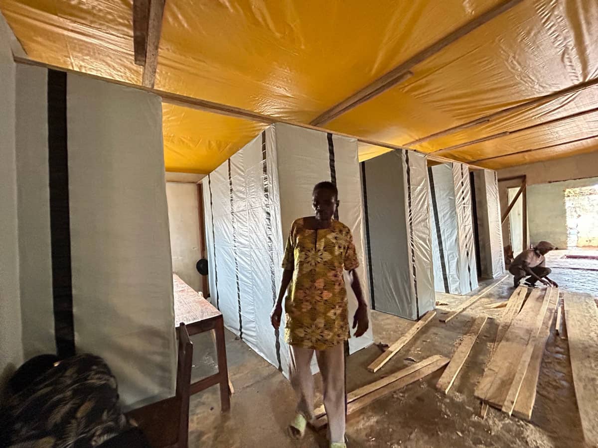 A man walking in a room lined with yellow and grey tarps.