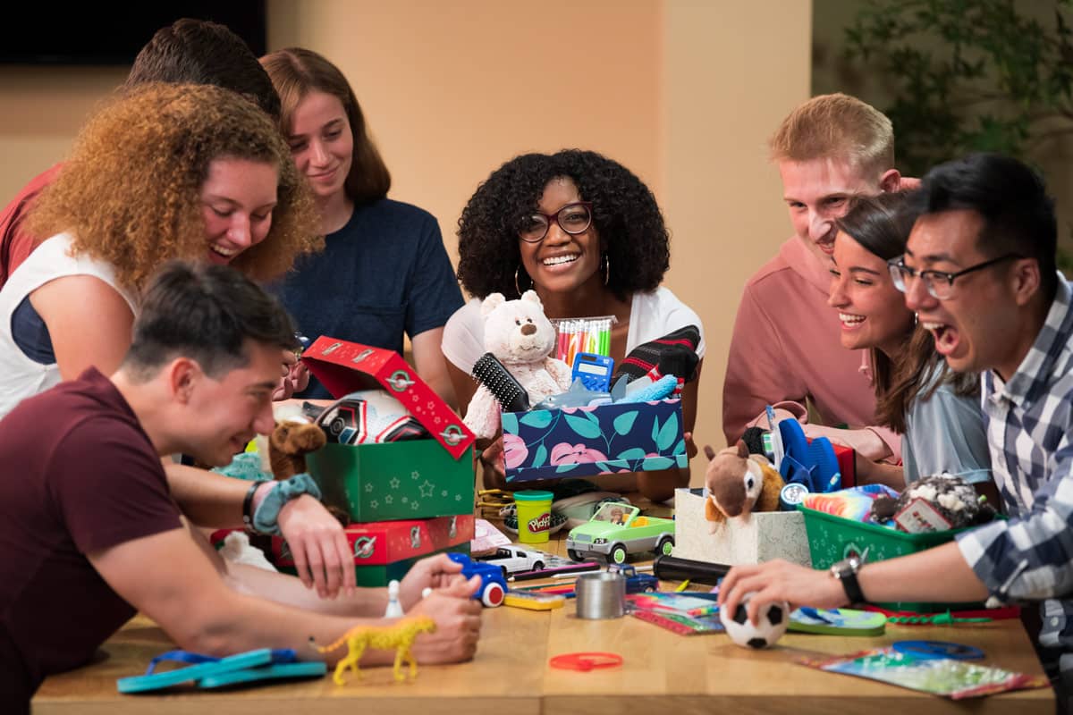 A group of young adults putting gifts into shoeboxes.