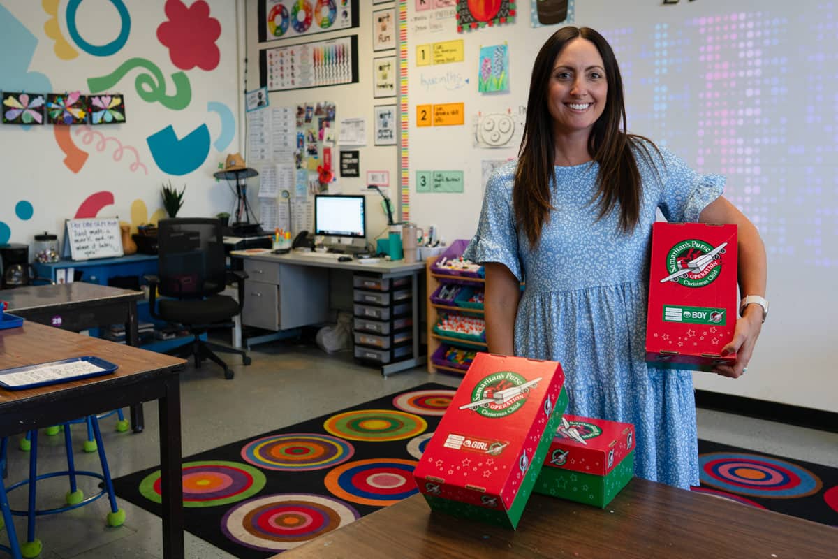 Woman standing in classroom with multiple shoebox gifts.