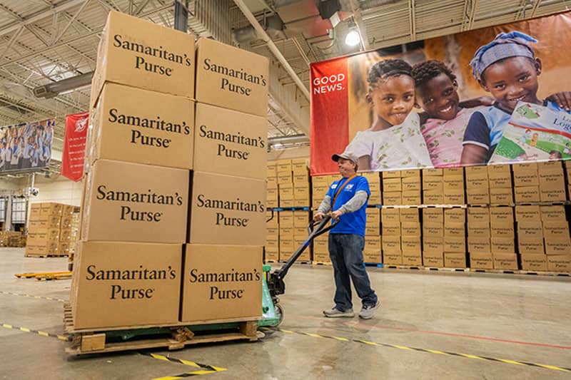 Man rolling a large cart of boxes.