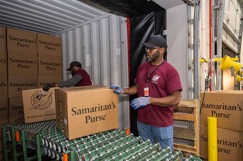 Man rolling a large cart of boxes.