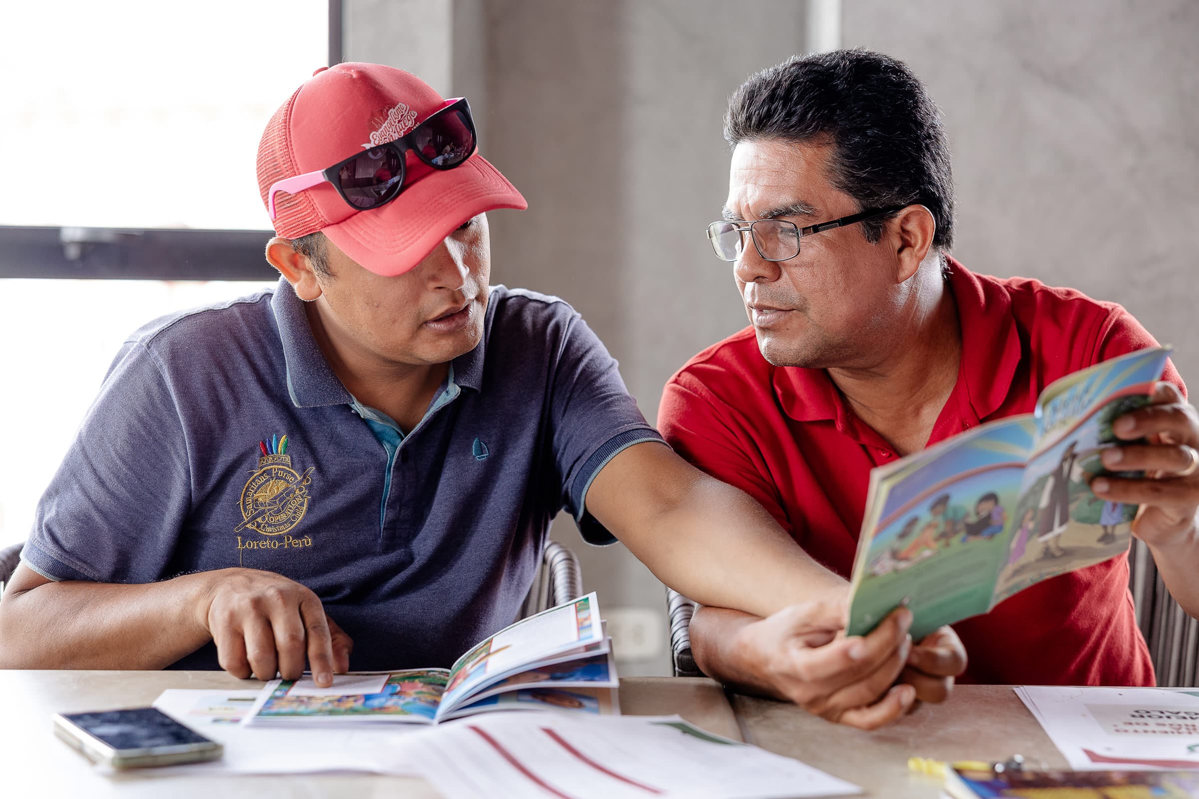 Two men studing The Greatest Gift booklet together at a table.