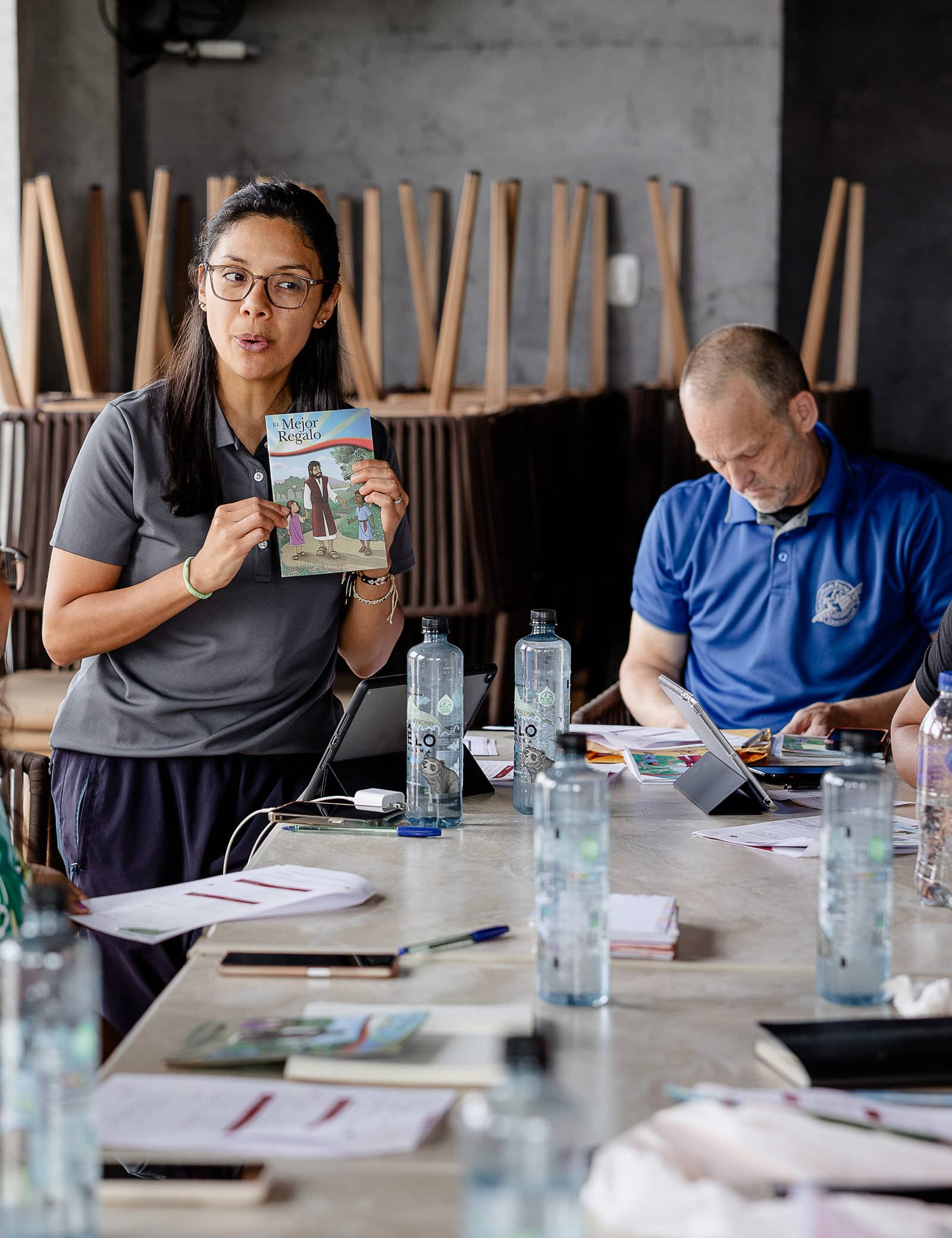 A woman showing The Greatest Gift to a group of leaders at a meeting.