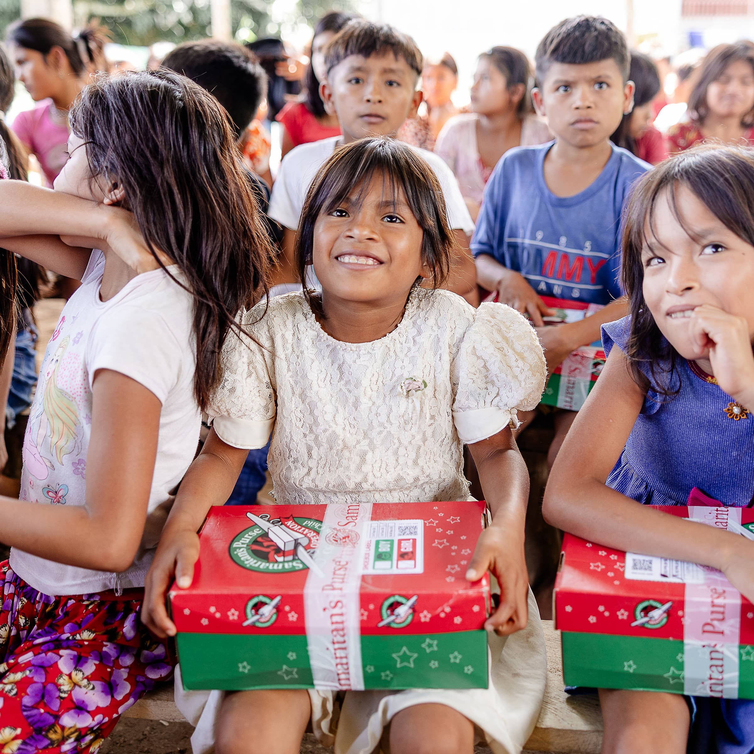 A girl smiling while holding her shoebox gift.