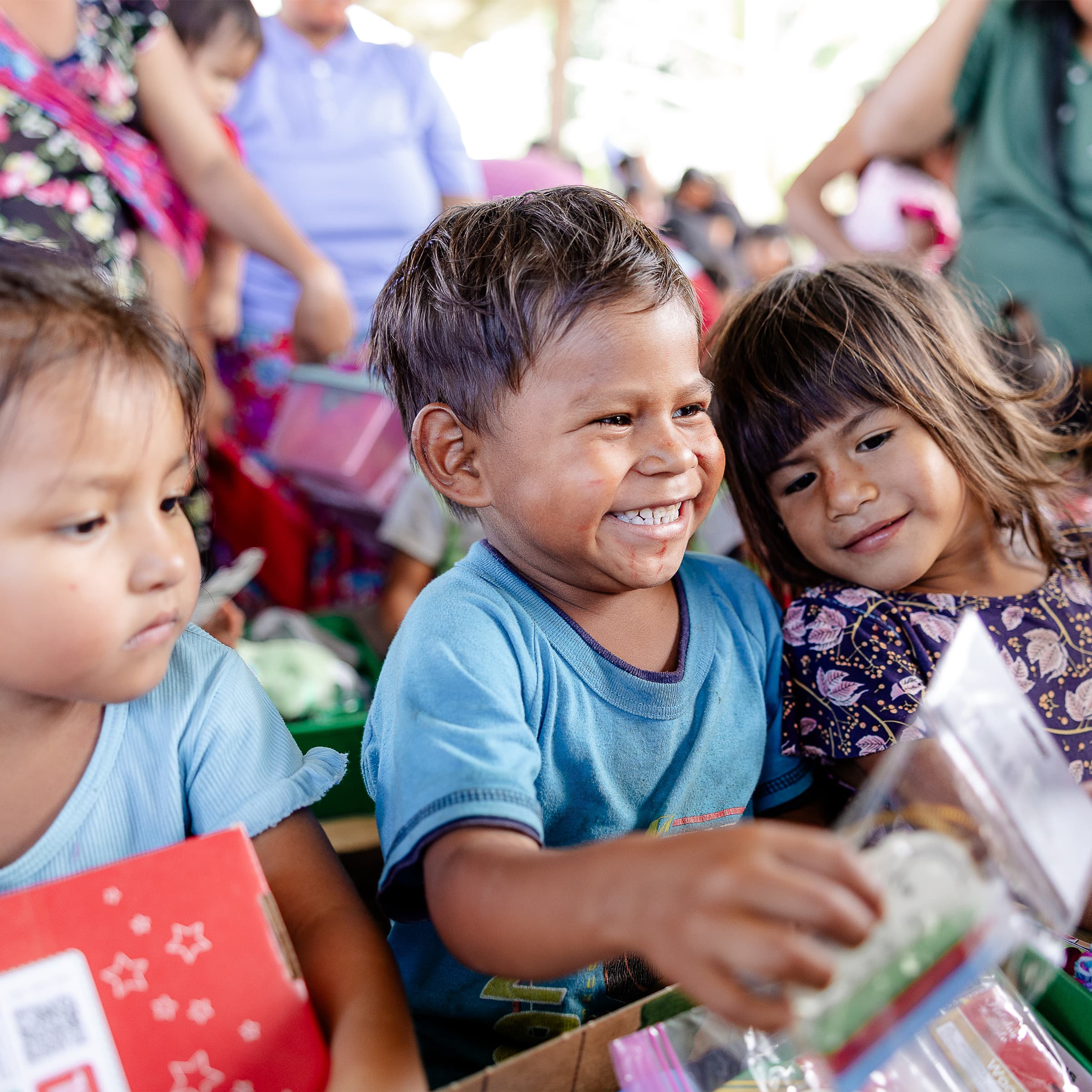 A boy smiling while opening his shoebox gift.