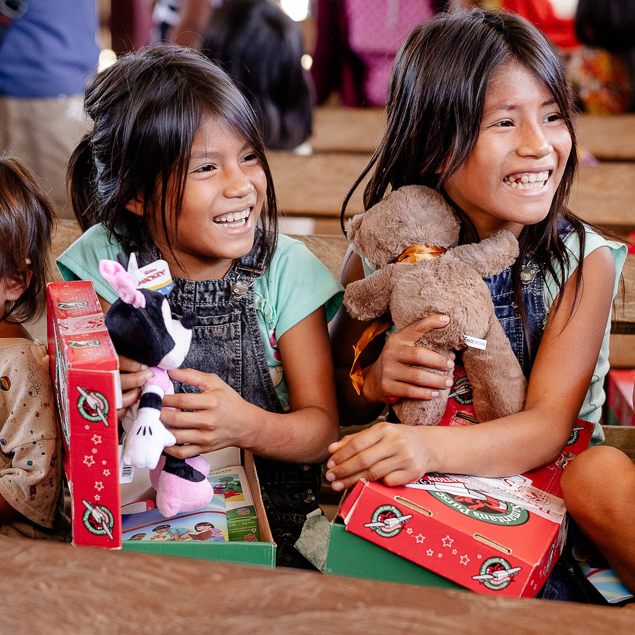 Two girls smiling while holding their toys from the shoebox gifts.
