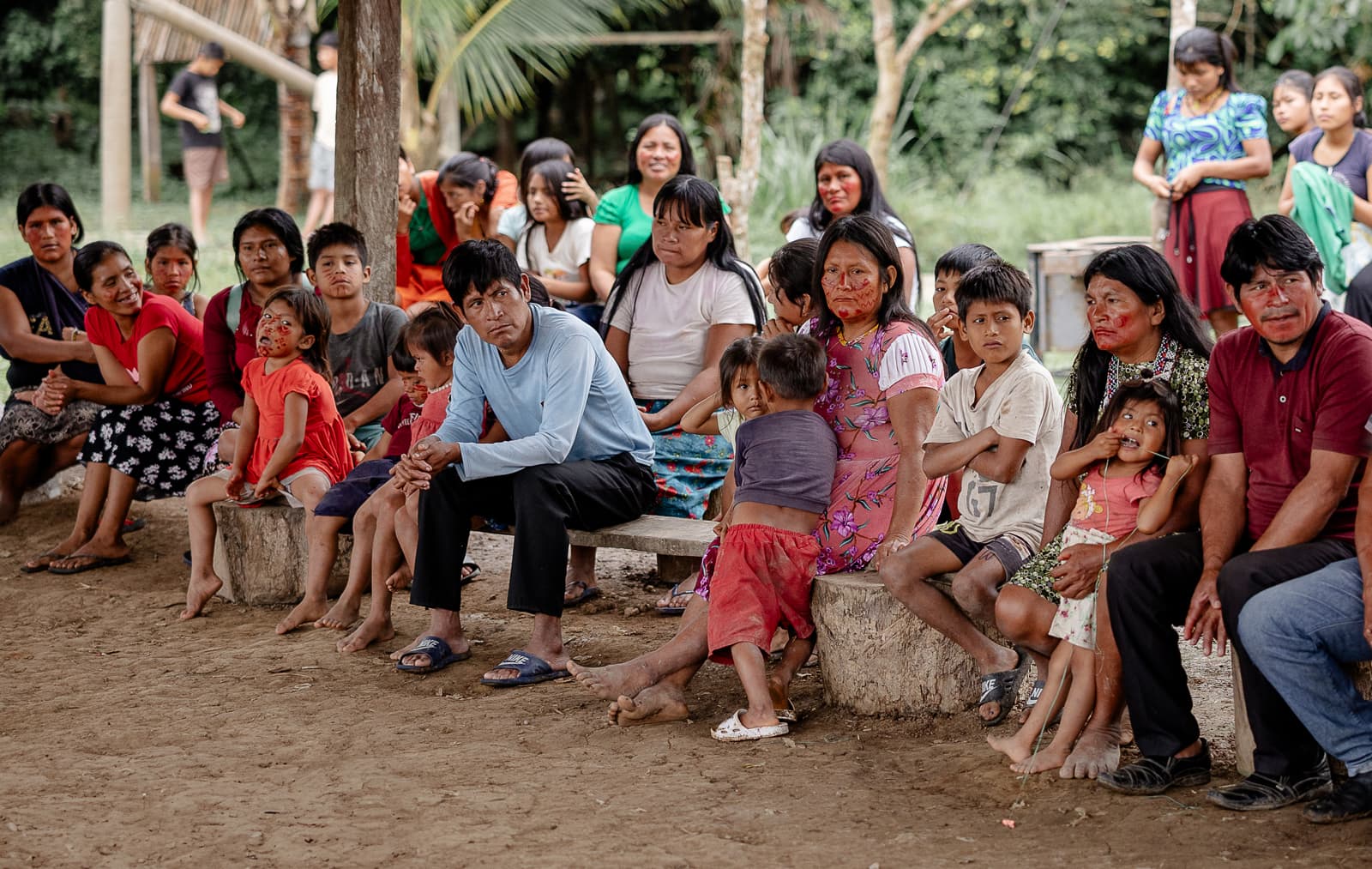 A group of children and parents sitting on benches under a pavilion.