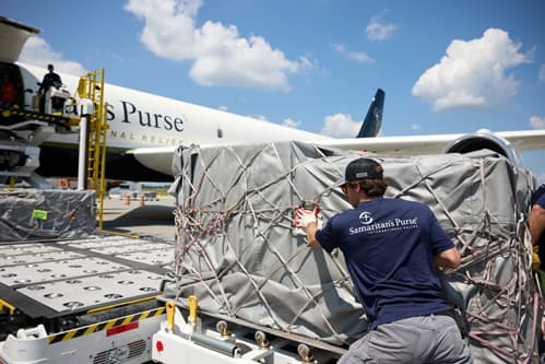 Multiple people loading gargo onto plane.