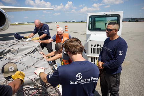Group of workers praying over cargo.