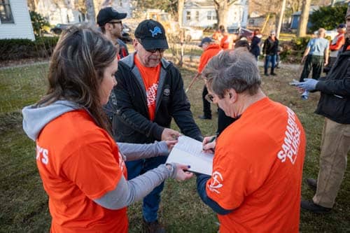 A group of volunteers in orange signing a bible for homeowner.