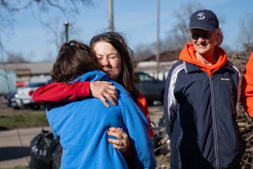 A volunteer hugging a homeowner.