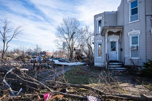Trees and debris on ground around house.