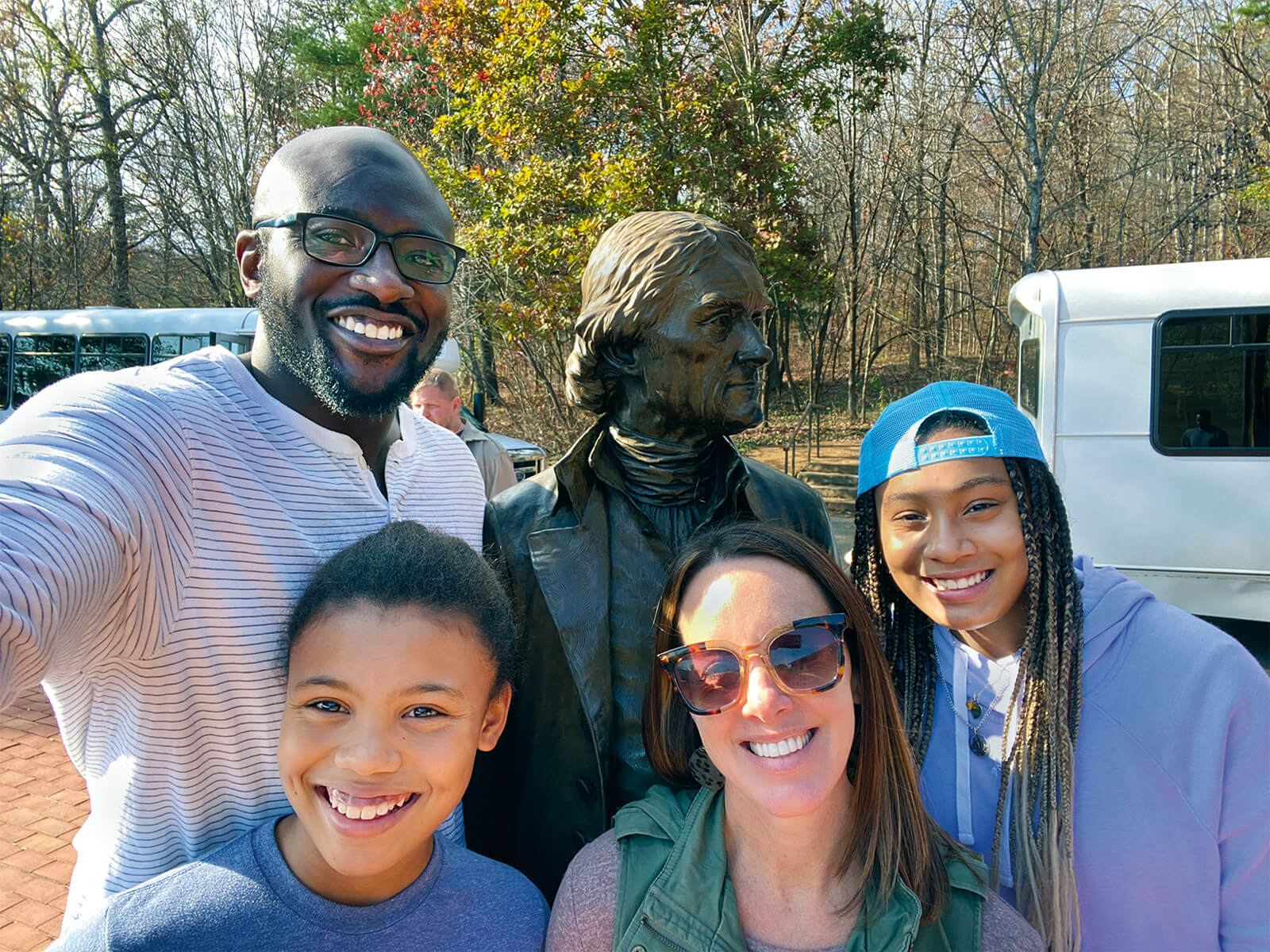 Four people smiling in front of statue.