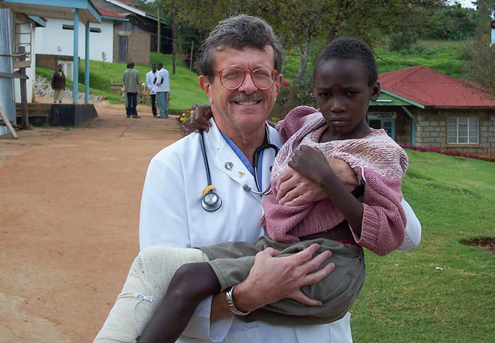 A doctor holding a child with a leg cast.