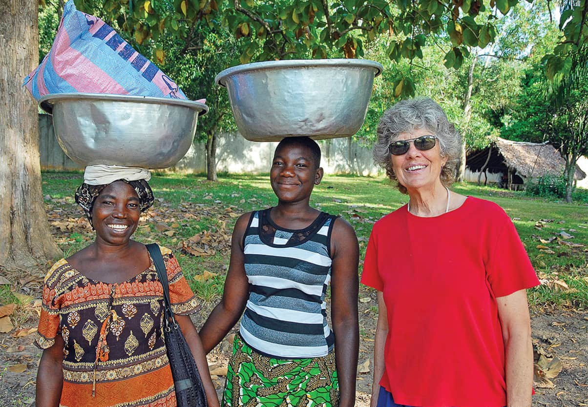 Three woman smiling;two woman have bowls on their heads.