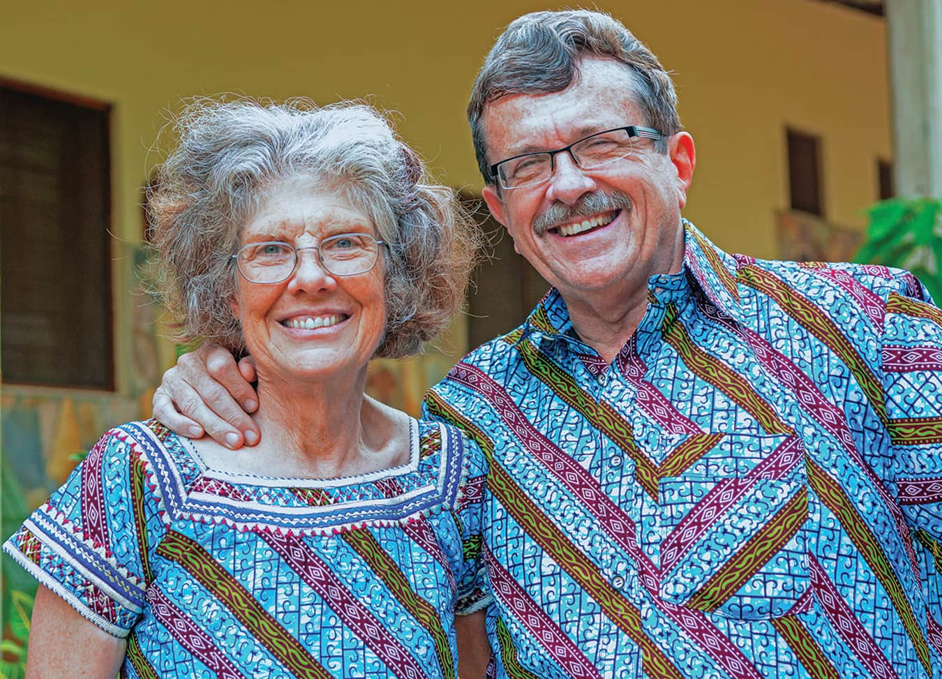 Man and woman smiling in matching colorful shirts.